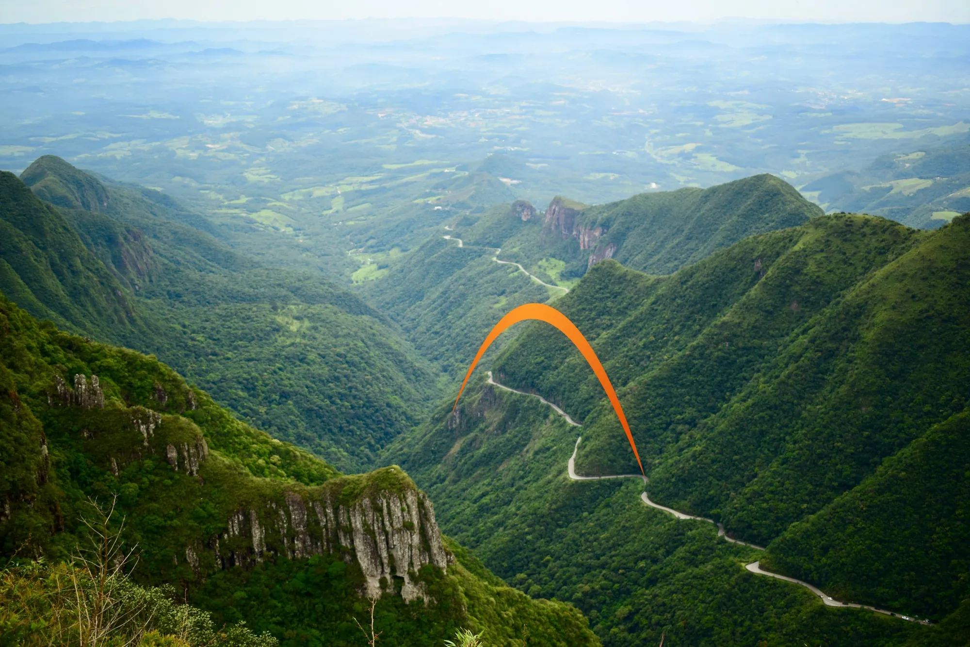 Strada tra le montagne della Serra brasiliana, con l’arco arancione Gen Brasil